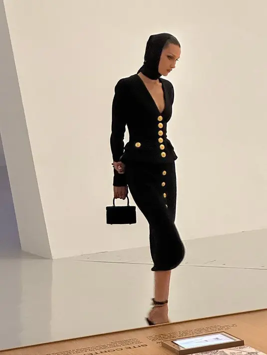 Gaun yang dikenakan memiliki potongan v-neck yang rendah. Dipadukan dengan syal hitam sebagai kerudung dan wadges bermotif bunga. [instagram/bellahadid]