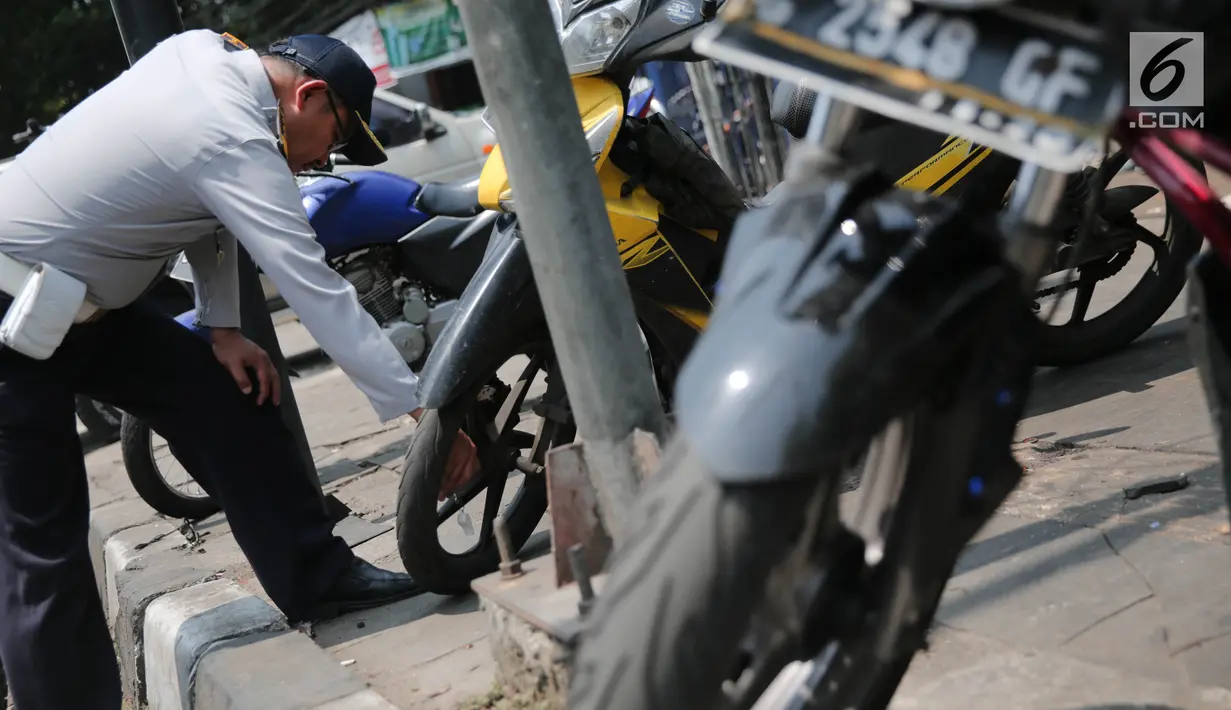 Petugas Dishub DKI menggembosi ban sepeda motor yang nekat parkir liar di trotoar sepanjang Jalan Kramat Raya, Senen, Jakarta, Jumat (22/9). Razia dilakukan untuk mengembalikan fungsi trotoar sebagai jalur pedestrian. (Liputan6.com/Faizal Fanani)