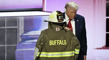 Donald Trump berdiri di samping jaket dan helm Corey Comperatore. (AP Photo/Charles Rex Arbogast)