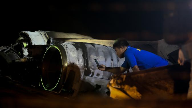 Petugas memeriksa puing-puing pesawat yang mengalami kecelakaan di ujung landasan pacu 24 di Bandara Internasional Ninoy Aquino, Manila, Filipina (29/3/2020).  Pesawat Lionair mengalami kecelakaan di Manila pada Minggu malam, 29 Maret 2020. Total delapan penumpang tewas. (Xinhua/Rouelle Umali)