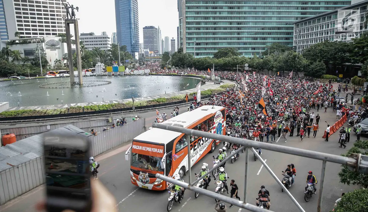Konvoi kendaraan Persija Jakarta dan Jakmania melintasi kawasan Bundaran HI dalam Pawai Juara Piala Presiden, Minggu (18/2). Ini adalah pertama kalinya Persija berhasil menjadi juara di kejuaraan pramusim tersebut. (Liputan6.com/Faizal Fanani)
