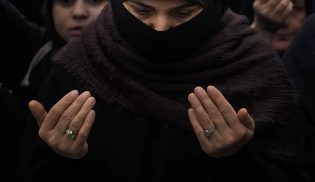 Seorang wanita berdoa saat protes di luar konsulat Swedia di Istanbul, Turki, Minggu (22/1/2023). Sejumlah wanita dan anak-anak juga menghadiri unjuk rasa di Istanbul. Di Ankara, unjuk rasa juga dilakukan di depan Kedutaan Besar Swedia. Protes terjadi pada Sabtu-Minggu kemarin waktu setempat. (AP/Khalil Hamra)
