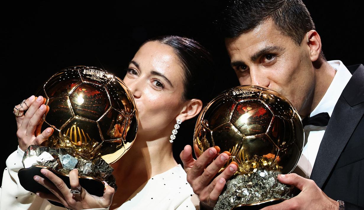 Pemain Barcelona, Aitana Bonmati (kiri) dan pemain Manchester City, Rodri mencium trofi Ballon d'Or pada acara yang berlangsung di Theatre du Chatelet, Paris, Selasa (29/10/2024) dini hari WIB. (AFP/Franck Fife)