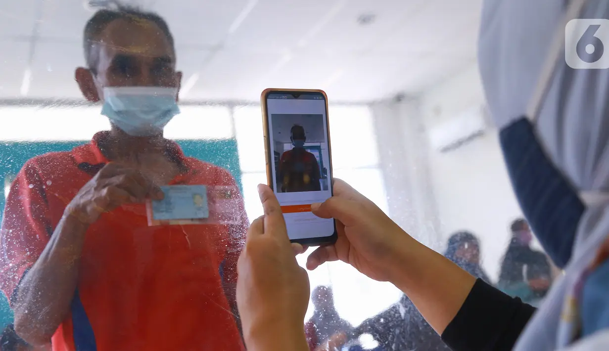 Petugas mengambil foto warga penerima Bantuan Sosial Tunai (BST) di Kelurahan Pondok Benda, Kecamatan Pamulang, Tangerang Selatan, Minggu (10/01/2021). Sebanyak 92.737 kepala keluarga tercatat sebagai penerima BST di wilayah Tangerang Selatan senilai Rp300 ribu. (Liputan6.com/Fery Pradolo)