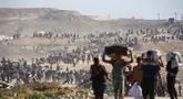 Orang-orang berjalan membawa tas-tas berisi bantuan kemanusiaan yang mereka terima di pusat distribusi yang dikelola oleh Yayasan Kemanusiaan Gaza (GHF) yang didukung Ameriks Serikat dan Israel, di koridor Netzarim, Nuseirat, Jalur Gaza tengah, pada 26 September 2025. (Eyad BABA/AFP)