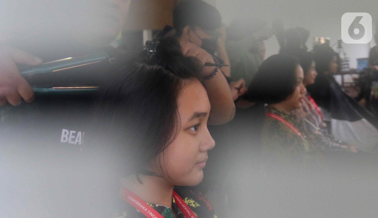 Pasukan Pengibar Bendera Pusaka (Paskibraka) melakukan prosesi potong rambut saat pemusatan diklat Paskibraka 2024 di Jakarta, Minggu (14/7/2024). (Liputan6.com/Herman Zakharia)