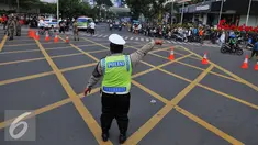 Seorang petugas polisi mengalihkan arus di kawasan Sarinah, Jakarta, Jumat (4/11). Pengalihan ini dilakukan karena aksi 4 November yang memadati tiga titik, yaitu di kantor Bareskrim Polri Balai Kota DKI, dan Istana Negara. (Liputan6.com/Angga Yuniar)