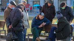 Para pria bermain catur di bangku kawasan pusat pejalan kaki di Kota Lviv, Ukraina, 20 Maret 2022. Kota Lviv menganggap dirinya sebagai pusat budaya Ukraina. (Alexey Filippov/AFP)