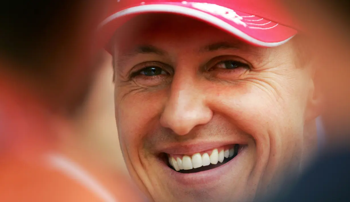 Pembalap Ferrari, Michael Schumacher tersenyum di paddock setelah sesi kualifikasi Formula 1 GP Bahrain di Sirkuit Sakhir pada 11 Maret 2006. (AFP/Loic Venance)