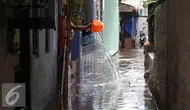 Seorang warga menguras air yang masuk kedalam rumahnya akibat banjir di kawasan Jatayu, Jakarta, Senin (21/11). Banjir disebabkan tingginya curah hujan dan buruknya saluran air serta meluapnya Kali Pesanggrahan. (Liputan6.com/Gempur M. Surya)