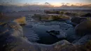 Lapisan es terbentuk di sepanjang pantai Danau Michigan sebelum matahari terbit di Chicago, Rabu (30/1). Dengan kondisi ini, suhu di Chicago, kota terbesar ketiga di AS, diperkirakan akan lebih dingin dari Antarktika di Kutub Selatan. (AP/Kiichiro Sato)