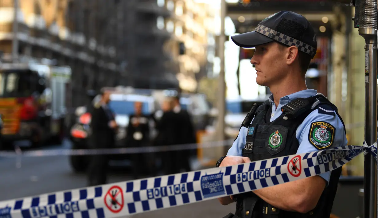 Seorang polisi berjaga di tempat kejadian setelah seorang pria menikam wanita dan berusaha menikam orang lain di pusat kota Sydney (13/8/2019). Pelaku penikaman berhasil ditangkap polisi setelah sejumlah warga melawan. (AFP Photo/Saeed Khan)