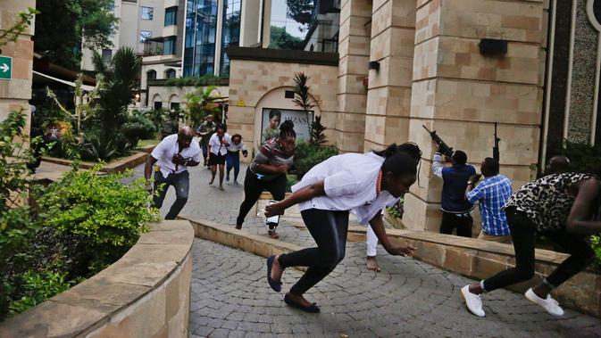 Warga melarikan diri saat pasukan keamanan memburu kelompok bersenjata yang menyerang sebuah kompleks hotel mewah di Nairobi, Kenya, Selasa (15/1). Polisi Kenya dibantu pasukan asing untuk melumpuhkan kelompok bersenjata. (AP Photo/Khalil Senosi)