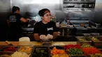 Maria Hidalgo (26) menyiapkan menu makanan di dapur Homegirl Cafe, Los Angeles, Senin (16/7). Kafe yang menyediakan sarapan dan makan siang khas Latin ini menawarkan pengalaman bersantap unik dengan mempekerjakan para mantan anggota geng. (AP/Jae C. Hong)