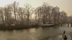 Tukang perahu menggunakan dayung memecahkan lapisan es di sepanjang bagian dalam Danau Dal pada pagi saat musim dingin di Srinagar (2/1/2023). Periode musim dingin yang keras selama 40 hari yang dikenal sebagai 'Chillai Kalan' memperketat cengkeramannya di Kashmir pada hari Senin karena suhu malam semakin turun. (AFP/Tauseef Mustafa)