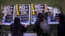 Pendukung migran Chili merobek poster anti-migran yang tersebar di sepanjang pusat kota Santiago, Chili, Minggu (20/8). Pemilihan Presiden akan dilakukan pada 19 November 2017 mendatang. (Esteban Felix/AP)