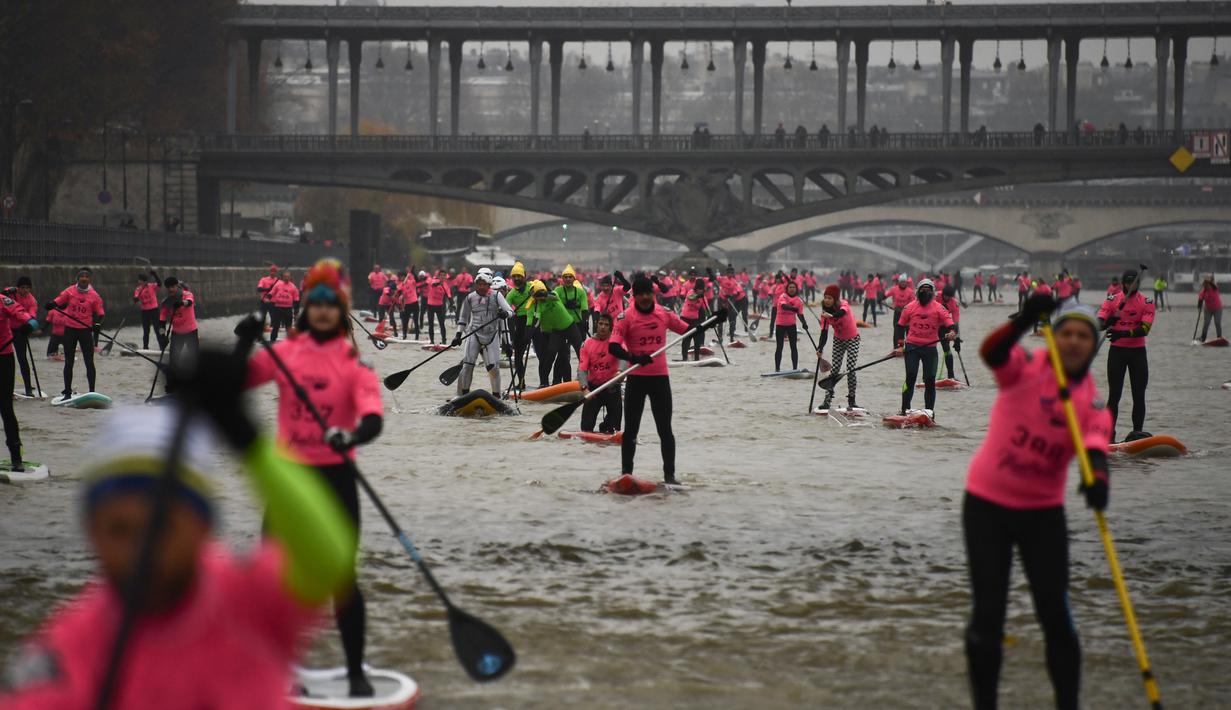 Para peserta ambil bagian dalam perlombaan dayung sambil berdiri pada Nautic SUP Paris di sepanjang sungai Seine, Paris, Minggu (3/12). Sekitar 700 peserta berpartisipasi menyeberangi sungai Seine dengan pemandangan kota Paris (AFP PHOTO/CHRISTOPHE SIMON)