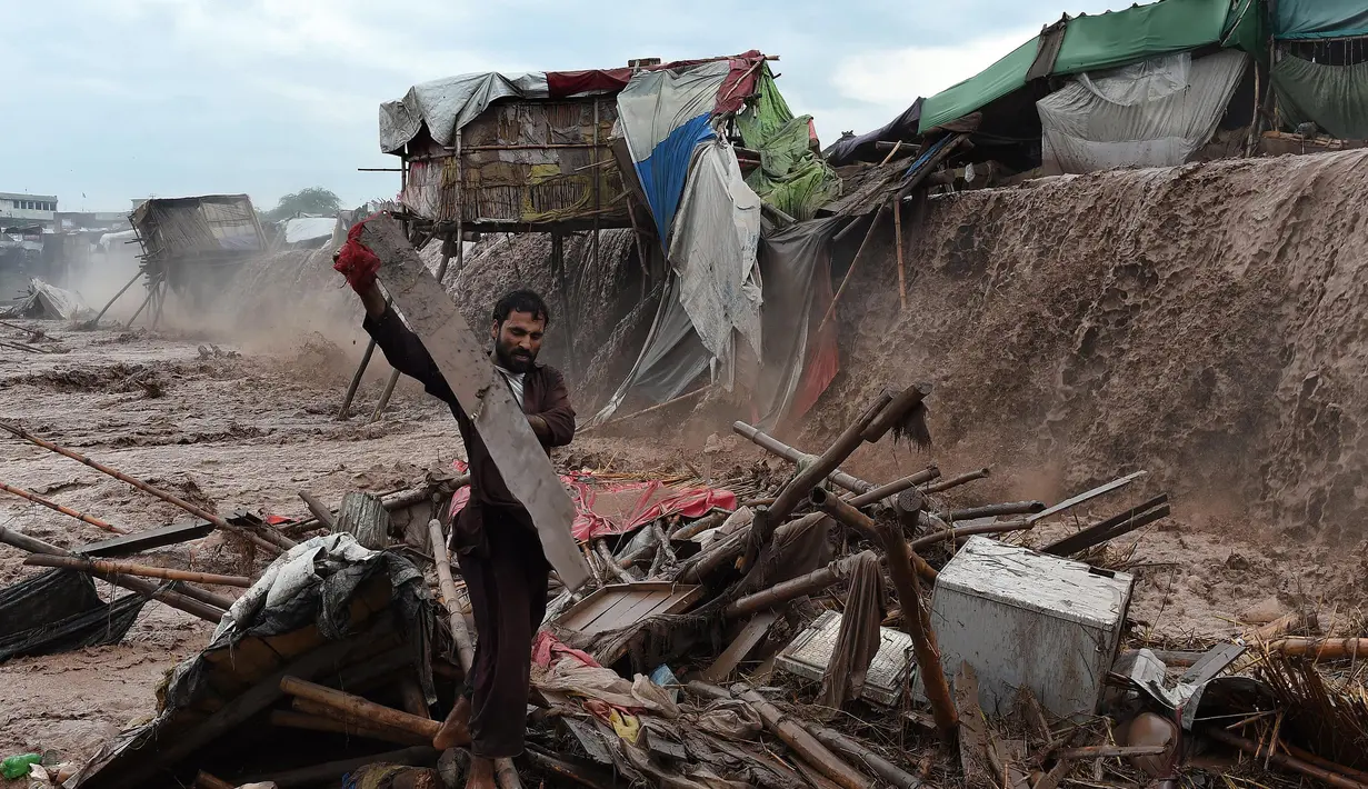 Warga berusaha menyelamatkan barang miliknya saat banjir bandang menerjang kawasan pasar di Peshawar, Pakistan, Minggu (3/4). Menurut badan otoritas bencana Pakistan musibah banjir dan tanah longsor menjadi penyebab banyaknya korban jiwa. (AFP/A Majeed)