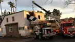 Petugas mengevakuasi mobil sedan putih yang tertancap di bangunan lantai dua klinik dokter gigi di Santa Ana, California, Minggu (14/1). Separuh badan mobil terjepit di gedung tersebut setelah melewati pembatas jalan. (Orange County Fire Authority via AP)