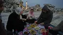 Anggota keluarga Al-Najar berbuka puasa selama bulan suci Ramadan di tengah reruntuhan bangunan yang hancur di Kota Gaza, Jumat 13 Maret 2026. Di tengah puing-puing bangunan yang nyaris rata dengan tanah, masyarakat Gaza tetap menjaga nuansa hangat kebersamaan Ramadan seperti biasanya. (AP Photo/Jehad Alshrafi)