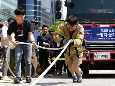 Petugas pemadam kebakaran Lim Sung-joo menarik sebuah truk pemadam kebakaran dengan seutas tali saat Safe Seoul Festival di Seoul, Korea Selatan, Kamis (9/5/2019). Safe Seoul Festival digelar untuk mengampanyekan kesadaran keselamatan. (AP Photo/Ahn Young-joon)