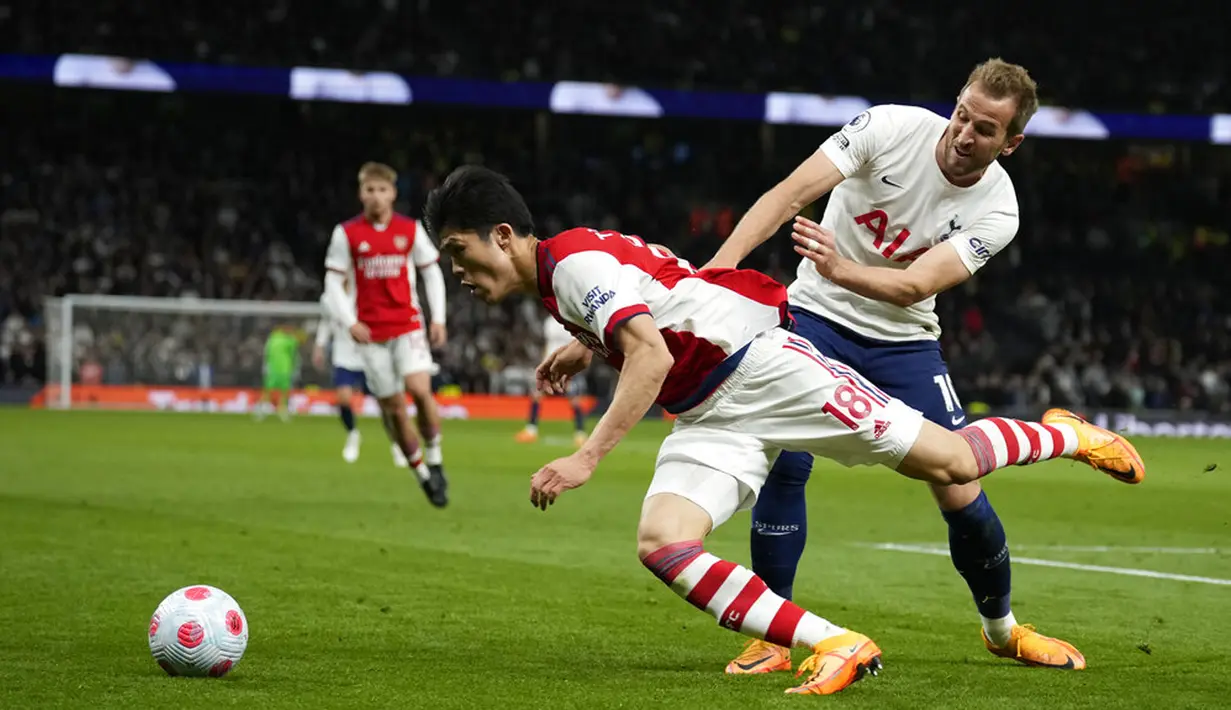 Pemain Tottenham Hotspur Harry Kane (kanan) berebut bola dengan pemain Arsenal Takehiro Tomiyasu pada pertandingan sepak bola Liga Inggris di Stadion Tottenham Hotspur, London, Inggris, 12 Mei 2022. Tottenham Hotspur menang 3-0. (AP Photo/Matt Dunham)