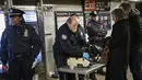 Petugas kepolisian memeriksa tas penumpang saat memasuki stasiun kereta bawah tanah Times Square pada jam sibuk malam di New York City, Senin (11/12). Sebelumnya ledakan bom terjadi di terminal bawah tanah kawasan Manhattan (Drew Angerer/Getty Images/AFP)