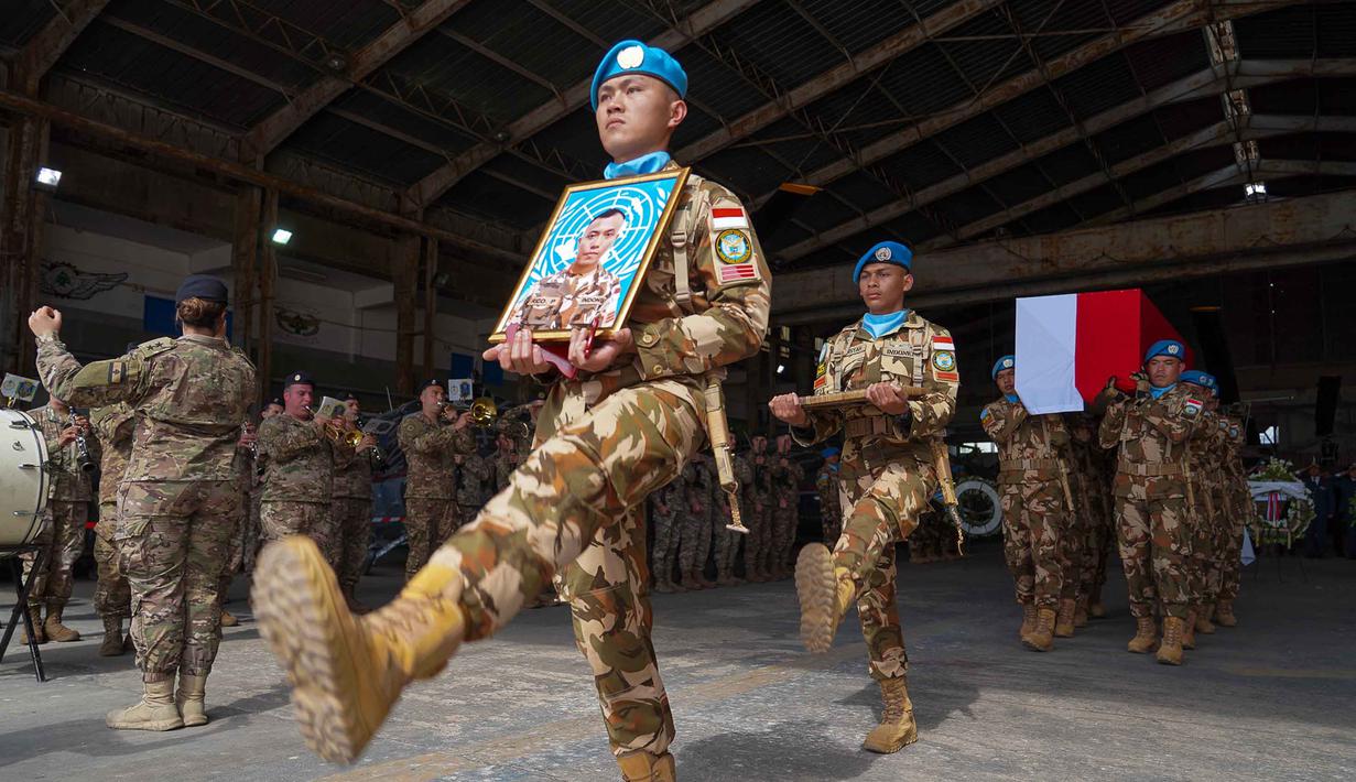 Foto yang diambil dan dirilis oleh Pasukan Sementara Perserikatan Bangsa-Bangsa di Lebanon (UNIFIL), menunjukkan rekan-rekan membawa peti jenazah dan foto seorang Tentara Nasional Indonesia, Kopral Rico Pramudia, saat upacara penghormatan di Bandara Internasional Lebanon, Beirut, pada 26 April 2026. Kontingen Pasukan Sementara Perserikatan Bangsa-Bangsa di Lebanon (UNIFIL) menggelar upacara penghormatan untuk Prajurit TNI Kopral Rico Pramudia. (Haidar Fahs/UNIFIL/AFP)