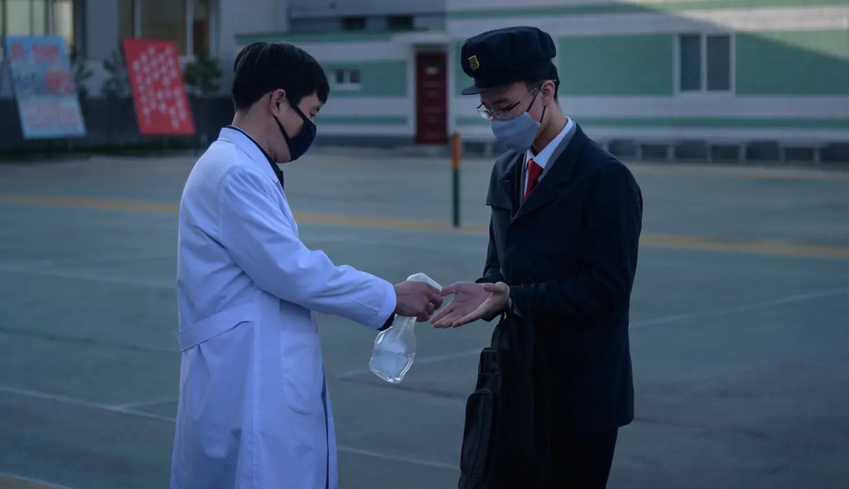 Petugas menyemprotkan cairan hand sanitizer kepada mahasiswa sebagai upaya mencegah penyebaran pandemi Covid-19 di Universitas Kedokteran Pyongyang, Rabu (22/4/2020). Korea Utara memberlakukan pembatasan ketat guna mengantisipasi penyebaran virus corona di negara tersebut. (KIM Won Jin/AFP)