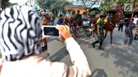 Warga mengabadikan momen simulasi kirab pernikahan Kahiyang Ayu dan Bobby Nasution, Medan, Rabu (22/11). Simulasi kirab ngunduh mantu Jokowi menjadi pusat perhatian warga sekitar. (Liputan6.com/Johan Tallo)