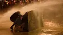 Demonstran antipemerintah berlindung dari semprotan air saat bentrok dengan polisi antihuru-hara dalam demonstrasi menentang pemerintahan baru dekat Parliament Square, Beirut, Lebanon, Rabu (22/1/2020). AP Photo/Hussein Malla)