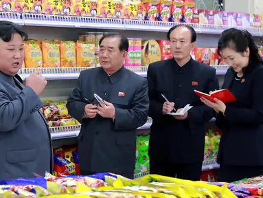 Pemimpin Korea Utara, Kim Jong-un berbincang dengan stafnya ketika berada di toko makanan saat mengunjungi Taesong Department Store setelah dibuka untuk umum di Korea Utara (8/4). (KCNA VIA AFP Photo)