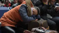 Seorang wanita tertidur saat menungu keberangkatan kereta api di Beijing, China (23/1). Tradisi mudik atau pulang kampung (Chunyun) ini sudah menjadi tradisi tahunan yang turun temurun bagi orang tionghoa. (AFP/Nicolas Asfouri)