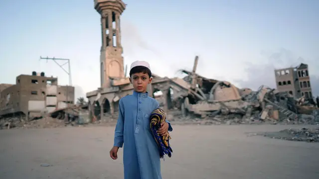 Seorang anak laki-laki Palestina, membawa sajadah, berfoto sebelum mengikuti salat Idul Adha di Khan Yunis, Gaza selatan. (Bashar Taleb/AFP)