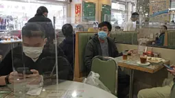 Pengunjung saat makan siang ditutupi panel plastik transparan untuk mengisolasi satu sama lain guna mencegah penyebaran virus corona di Hong Kong, Rabu, (12/2/2020). WHO kini menyebut virus tersebut dengan nama Covid-19, yang merupakan singkatan dari penyakit coronavirus 2019. (AP Photo/Kin Cheung)