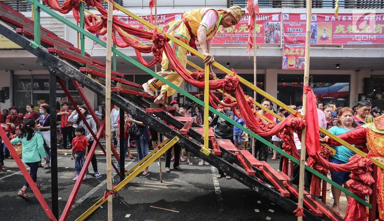 Tatung pria berjalan menuruni tangga dari susunan tombak saat beratraksi dalam Festival Cap Go Meh 2570 di Seasons City, Jakarta,  Minggu (24/3). Festival ini bertujuan untuk melestarikan kebudayaan Indonesia. (Liputan6.com/Fery Pradolo)
