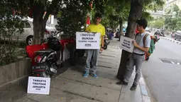 Koalisi Pejalan Kaki menunjukkan poster yang berisi imbauan saat melakukan aksi Tamasya Trotoar Kita di Jalan Medan Merdeka Selatan, Jakarta, Minggu (24/6). Acara ini juga dilakukan untuk mememperingati HUT Jakarta ke-491. (Liputan6.com/Arya Manggala)