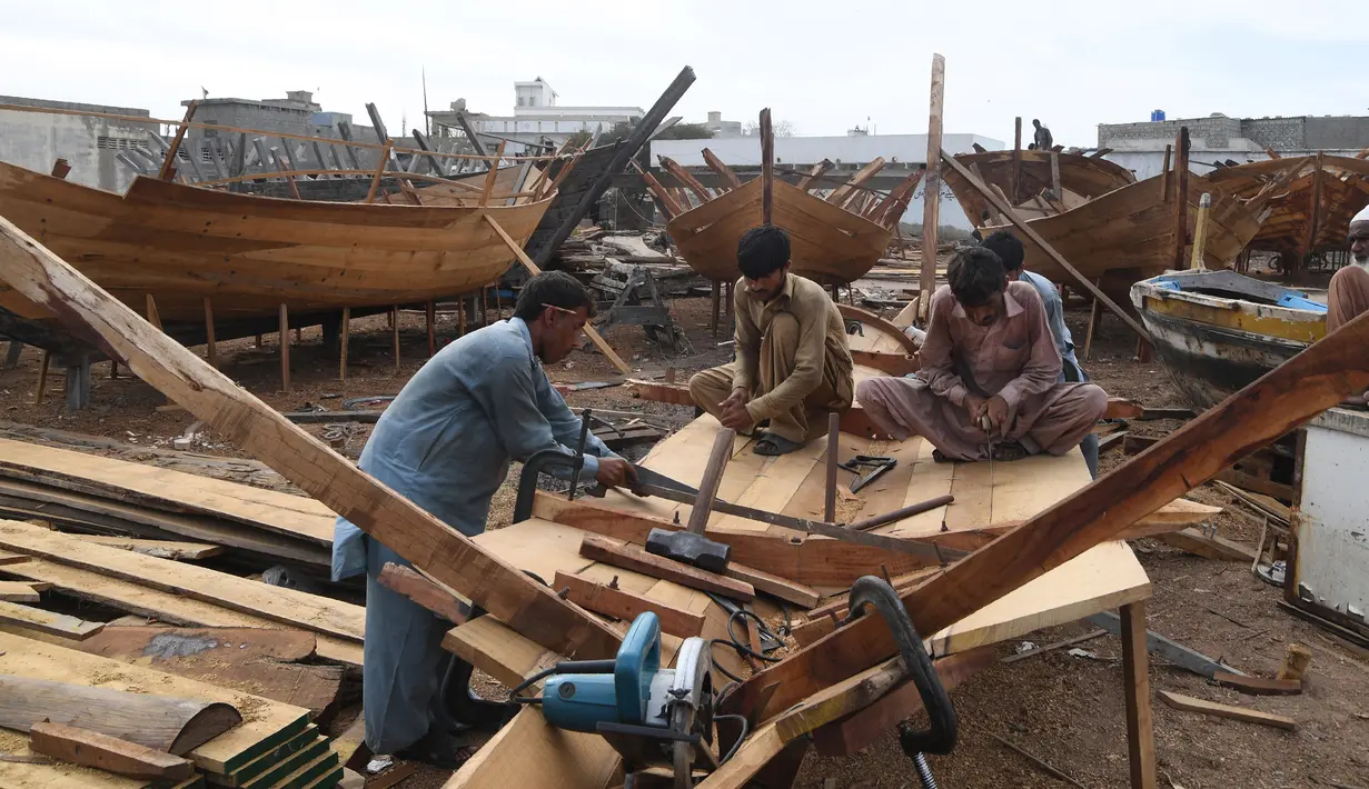 Tukang kayu Pakistan menyelesaikan pembuatan kapal penangkap ikan di sebuah pelabuhan di Karachi (3/4). Pembuatan kapal buatan Pakistan menghasilkan ratusan kapal setiap tahun untuk memenuhi permintaan industri perikanan setempat. (AFP Photo/Asif Hassan)