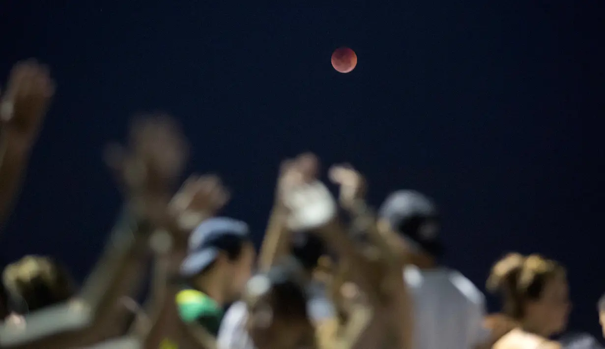 Fenomena gerhana bulan total "Micro Blood Moon" terlihat dari atas pantai Arpoador di Rio de Janeiro, Brasil, Jumat (27/7). Gerhana bulan terlama pada abad ini dapat disaksikan di seluruh dunia dengan mata telanjang. (AP/Silvia Izquierdo)