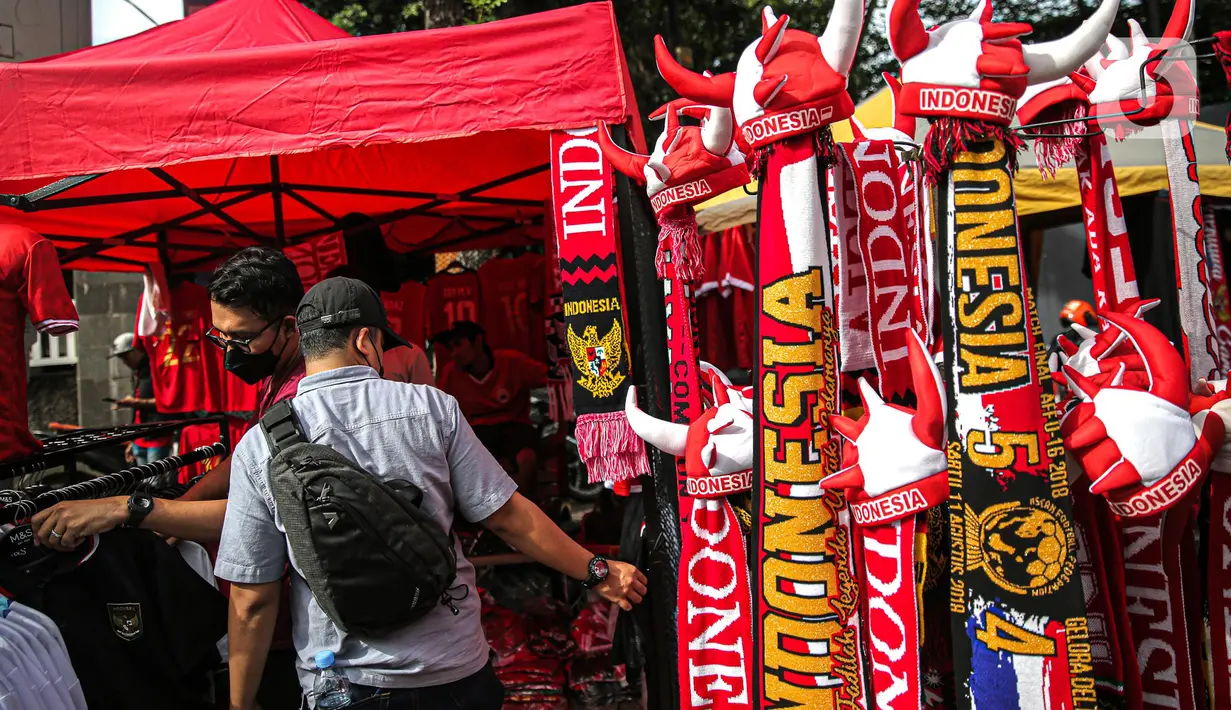 Suporter memilih atribut Timnas Indonesia jelang pertandingan AFF 2022 antara Indonesia melawan Thailand di Stadion Gelora Bung Karno, Jakarta, Kamis (29/12/2022). Atribut timnas Indonesia seperti kaos, syal, dan topi dijual dengan kisaran harga Rp35.000 hingga Rp75.000. (Liputan6.com/Faizal Fanani)