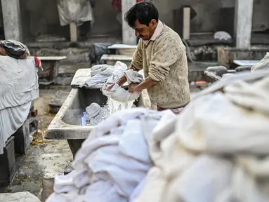 Seorang tukang cuci mencuci pakaian di binatu terbuka, yang secara lokal disebut 'Dhobi Ghat' di New Delhi, India pada 14 Maret 2022. Dhobi Ghat adalah tempat yang menyediakan layanan cuci dengan cara tradisional. (Money SHARMA / AFP)