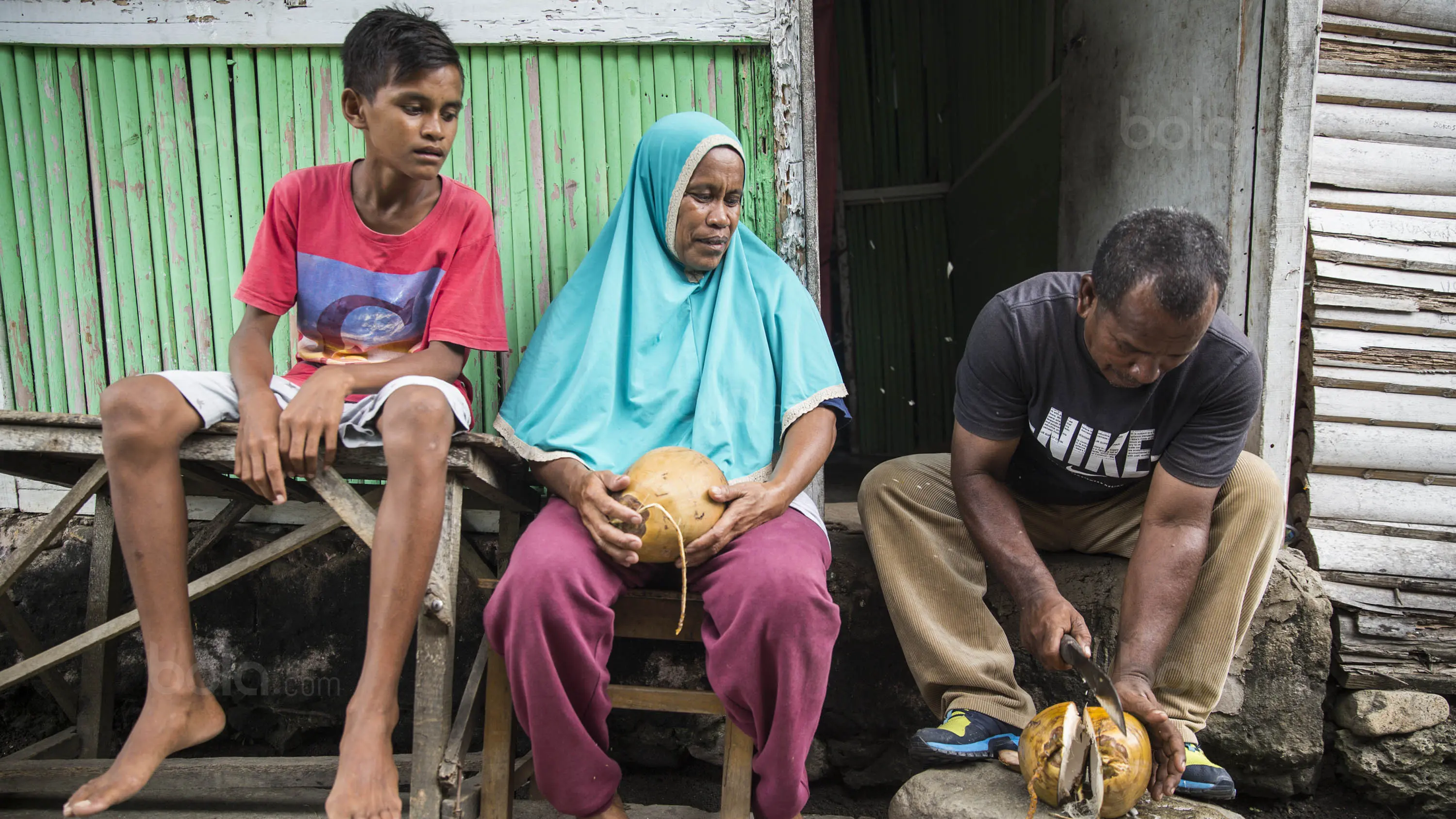 Pesepak bola SSB Tulehu Putra, Ilham Lestaluhu dibekali kelapa sebelum latihan oleh sang ayah. (Bola.com/Vitalis Yogi Trisna)