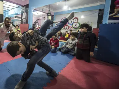 Seorang anak membanting temannya saat latihan di Akademi Olahraga Suriah di Alexandria, Mesir (4/1). Akademi olahraga ini didirkan oleh pengungsi Suriah yang bernama Amir al-Awad. (AFP/Khaled Desouki)