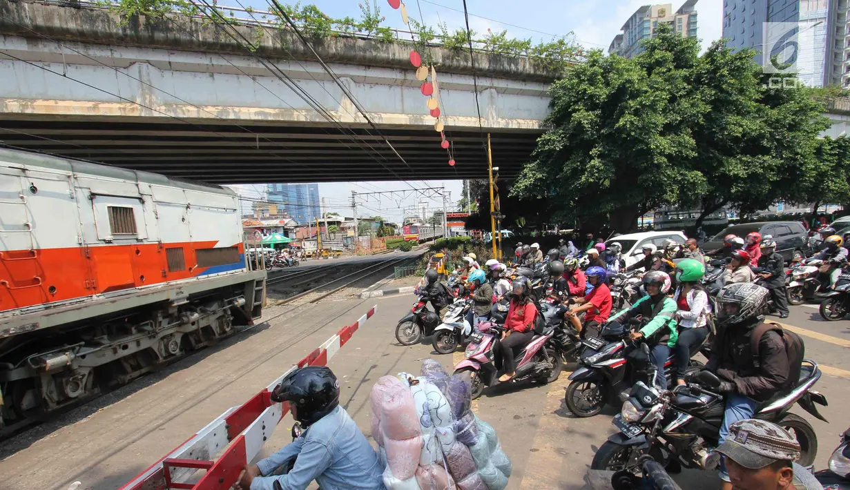 Pengendara menanti di pintu perlintasan kereta sebidang di Jalan KH Mas Mansyur, Jakarta, Senin (30/10). Perlintasan sebidang ini rencananya segera ditutup karena dianggap menjadi salah satu titik kemacetan di Jakarta Pusat. (Liputan6.com/Angga Yuniar)