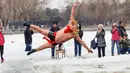 Seorang perenang musim dingin yang mengenakan kostum melompat ke dalam danau yang sebagian membeku di Shenyang, provinsi Liaoning, China, Selasa (19/2). Mereka percaya berendam di sungai dengan suhu yang ekstrem baik untuk kesehatan. (Photo by STR / AFP)