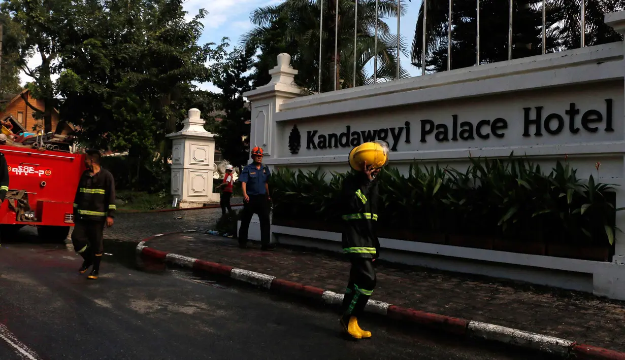 Petugas pemadam kebakaran saat berada di depan Hotel Istana Kandawgyi saat terjadi kebakaran di Yangon, Myanmar (19/10). Api telah melahap hotel bintang lima yang sering dikunjungi wisatawan asing di kota Yangon, Myanmar. (AP Photo/Thein Zaw)
