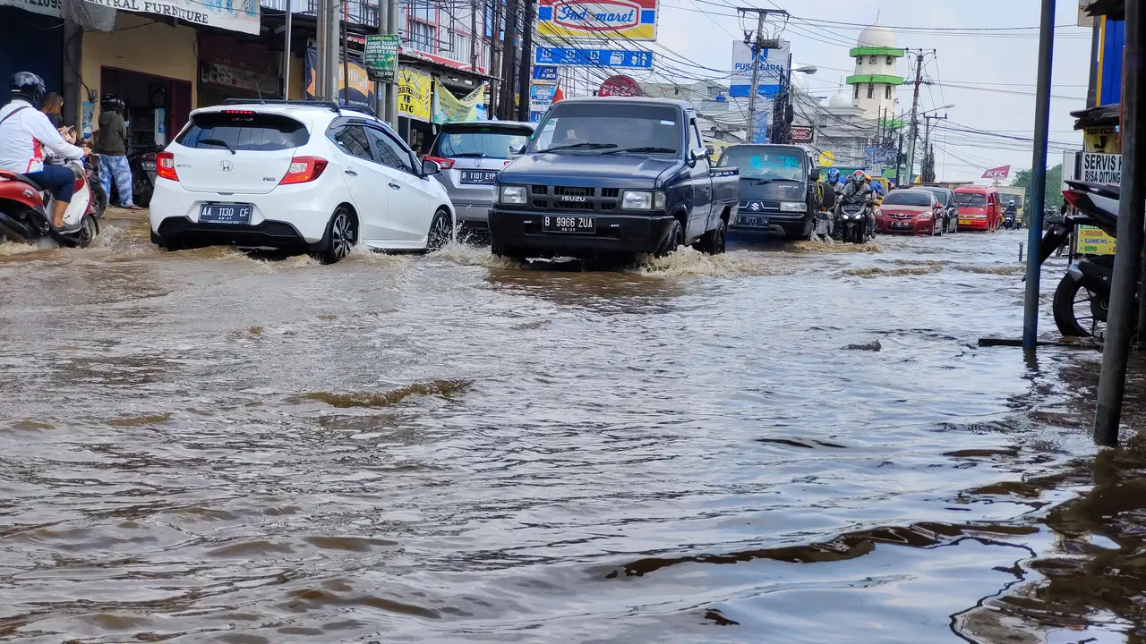 Sejumlah pengendara melintasi luapan air Kali Licin di Jalan Raya Sawangan, Kecamatan Pancoran Mas, Kota Depok.