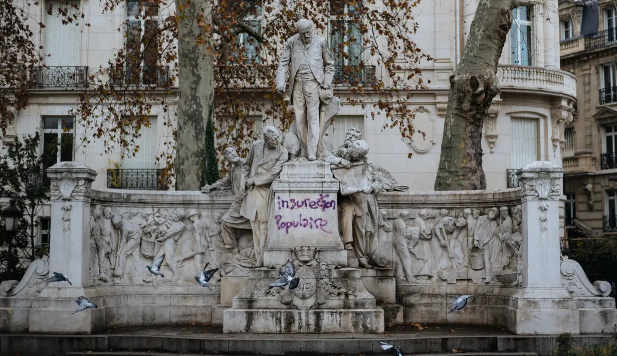 Grafiti bertuliskan 'insureksi populer' tertulis pada patung dekat Arc de Triomphe, Paris, Prancis, Minggu (2/12). Rakyat menuding kenaikan pajak bahan bakar berdampak pada risiko meningkatnya biaya hidup. (AP Photo/Kamil Zihnioglu)