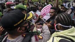 Polisi dan tentara saling dorong dengan masyarakat Papua yang memperingati Operasi Trikora 19 Desember 1961 di Patung Kuda, Jakarta, Sabtu (19/12/2020). Salah satu tuntutan massa adalah penghentian segala bentuk diskriminasi dan intimidasi terhadap mahasiswa Papua Barat. (Liputan6.com/Johan Tallo)