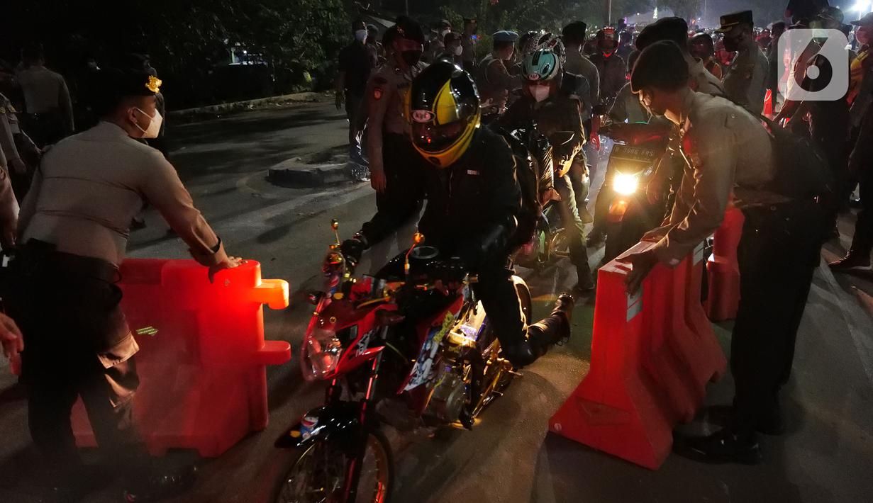 Polisi membuka pembatas jalan saat pemudik motor melintas di posko penyekatan mudik di Kedungwaringin, Kabupaten Bekasi, Jawa Barat, Selasa (11/5/2021) dini hari. Polisi kembali memberlakukan diskresi terhadap pemudik motor karena jumlahnya tidak terbendung. (Liputan6.com/Herman Zakharia)